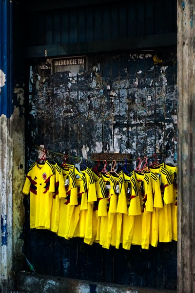 一群穿着黄黑长袖衬衫的男人站在棕色的水泥墙旁边